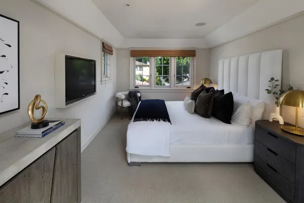 a bedroom with a bed and a flat tv screen on the dresser