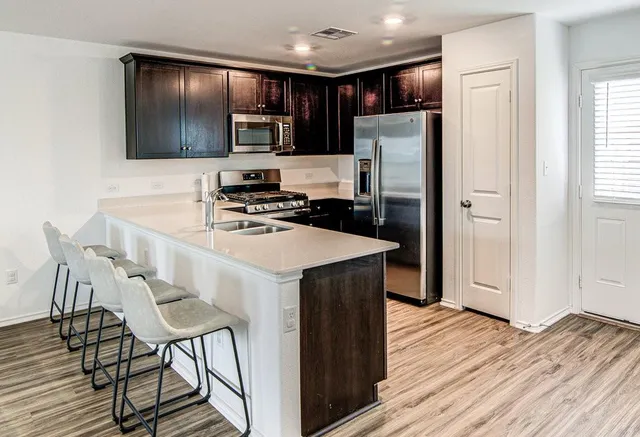 a kitchen with a refrigerator a microwave a stove and wooden floor