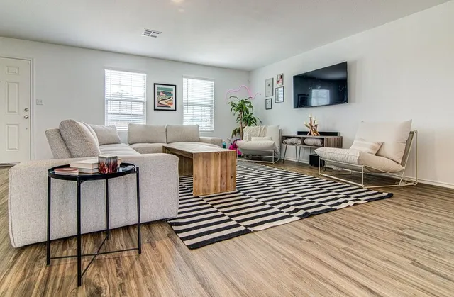 a living room with furniture a flat screen tv and a wooden floor