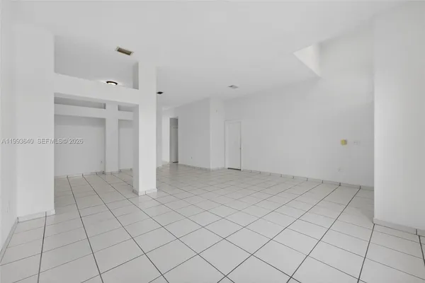a view of an empty room and chandelier fan