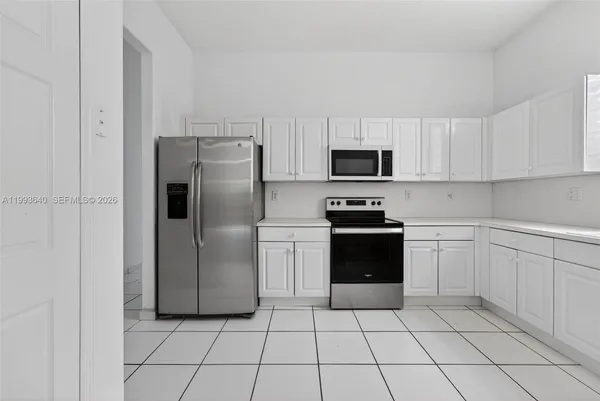 a kitchen with white cabinets and stainless steel appliances
