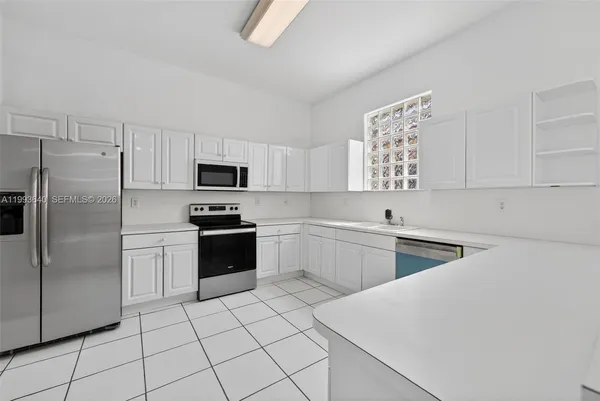 a kitchen with white cabinets and sink