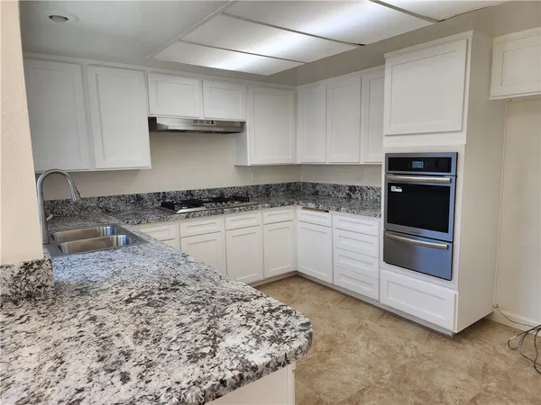 a kitchen with granite countertop a stove sink and cabinets