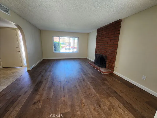 an empty room with wooden floor fireplace and windows