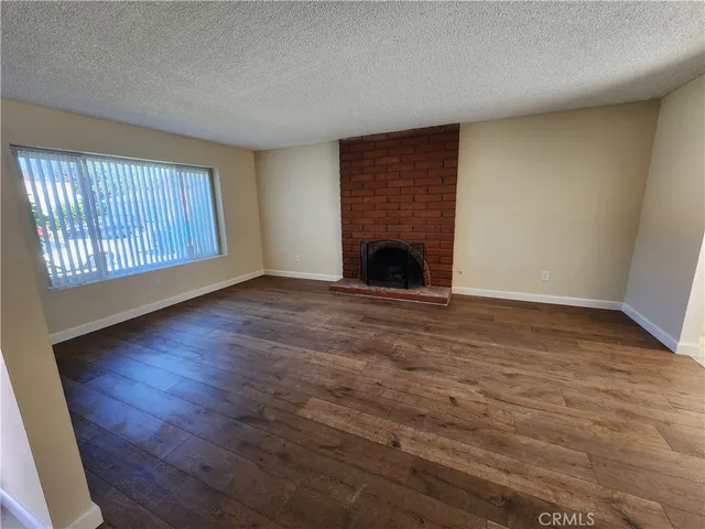 an empty room with wooden floor fireplace and windows
