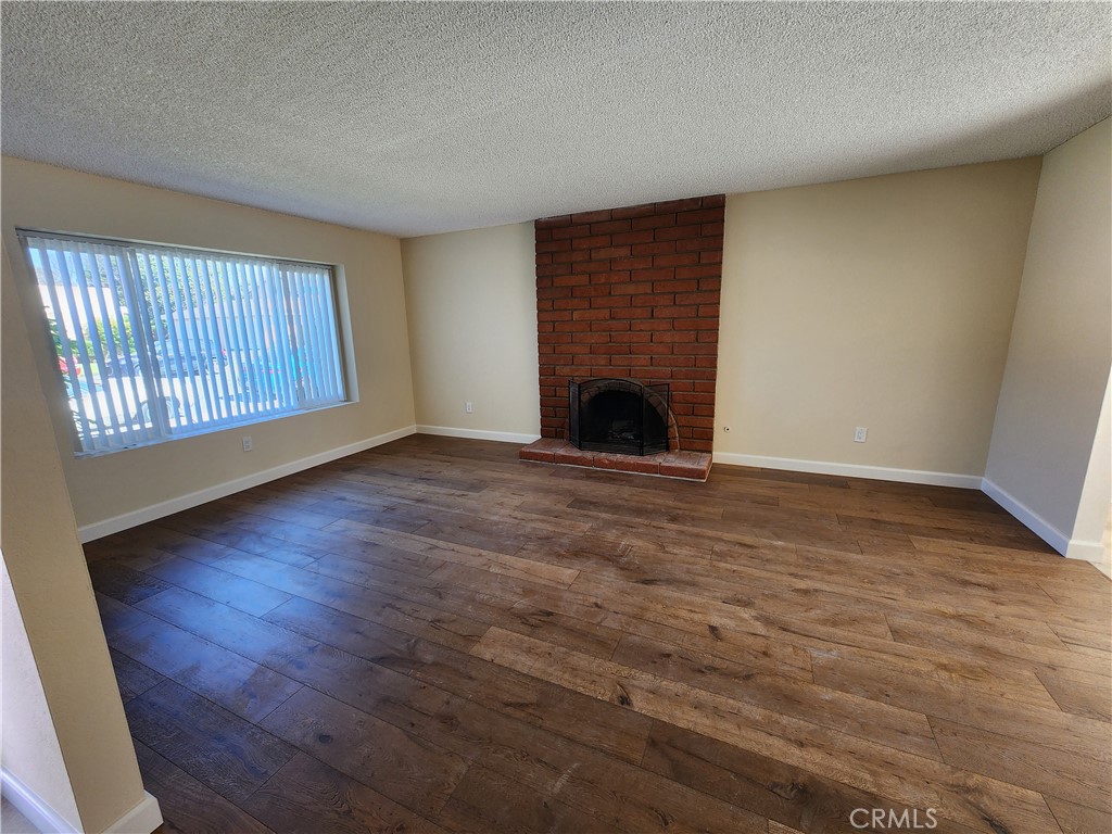 402 West Kelly Avenue, Unit A Orange, CA 92866 - Photo 3 of 13 an empty room with wooden floor fireplace and windows