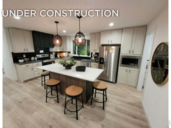 a kitchen with stainless steel appliances kitchen island granite countertop a refrigerator a stove a microwave oven a sink and a dining table with wooden floor