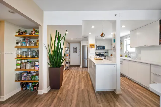 a kitchen with stainless steel appliances a sink a stove a refrigerator cabinets and wooden floor