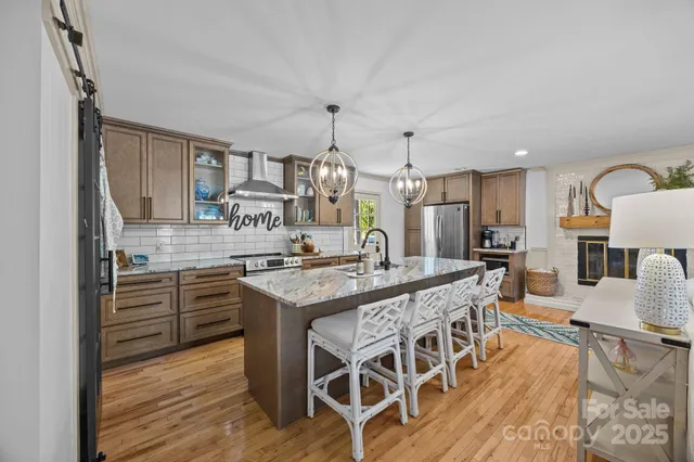 a kitchen with stainless steel appliances granite countertop a kitchen island a stove and a wooden floors