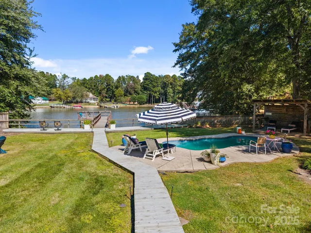 a view of swimming pool with outdoor seating and trees in the background