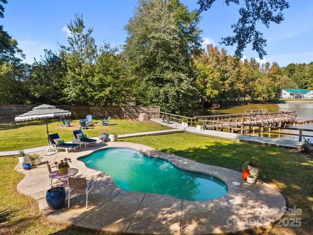 a view of a swimming pool with a patio and a yard