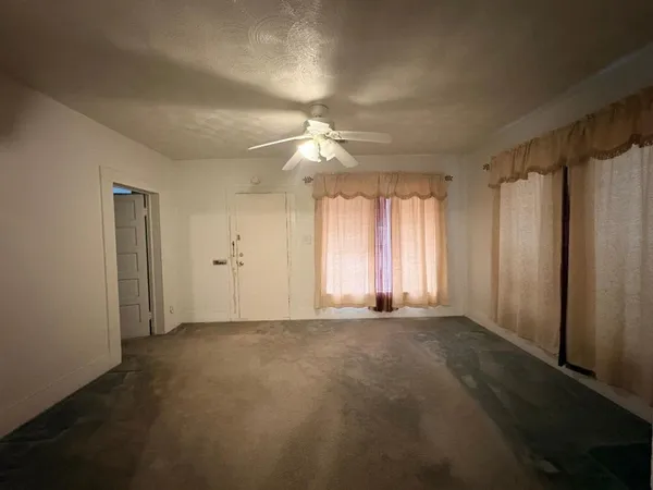 an empty room with windows and fan