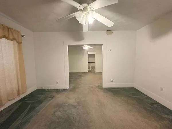 an empty room with a ceiling fan and a window