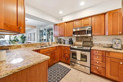 a kitchen with stainless steel appliances granite countertop a stove a sink and a microwave