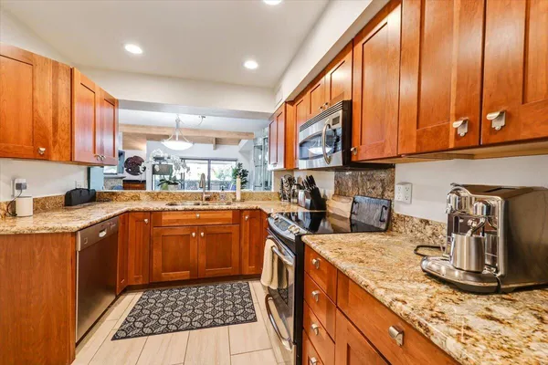 a kitchen with stainless steel appliances granite countertop a stove a sink and a microwave