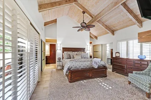 a spacious bedroom with a bed a dresser and a chandelier