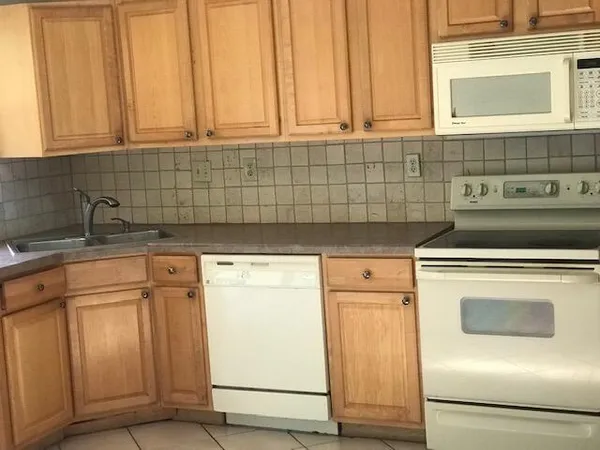 a kitchen with granite countertop white cabinets and white appliances