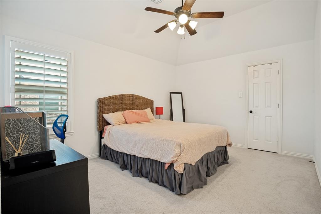 1461 Ramsbury Lane Prosper, TX 75078 - Photo 21 of 30 Vaulted ceiling bedroom with a wood-bladed ceiling fan, white paneled door, and plantation shutters