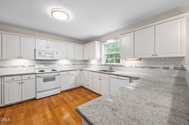 a kitchen with granite countertop wooden cabinets stainless steel appliances a sink and a window