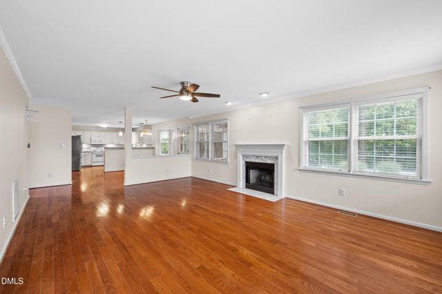 a view of an empty room with wooden floor and a fireplace