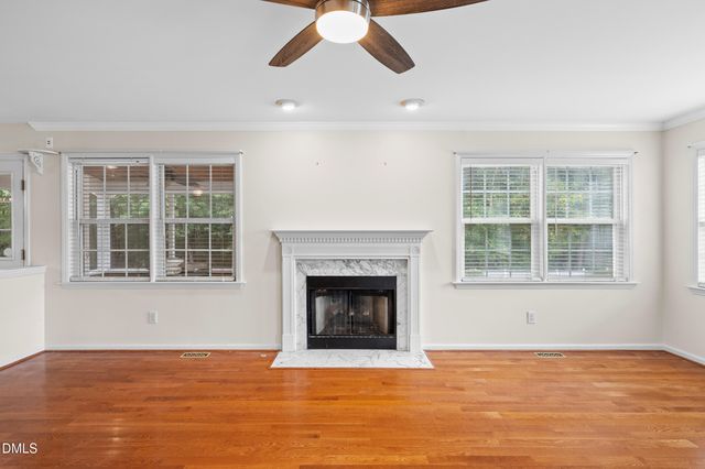 an empty room with windows fireplace and wooden floor