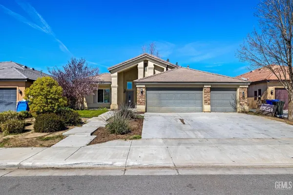a front view of a house with garage and plants