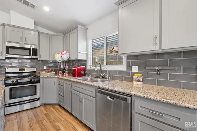 a kitchen with granite countertop a sink stainless steel appliances and counter space