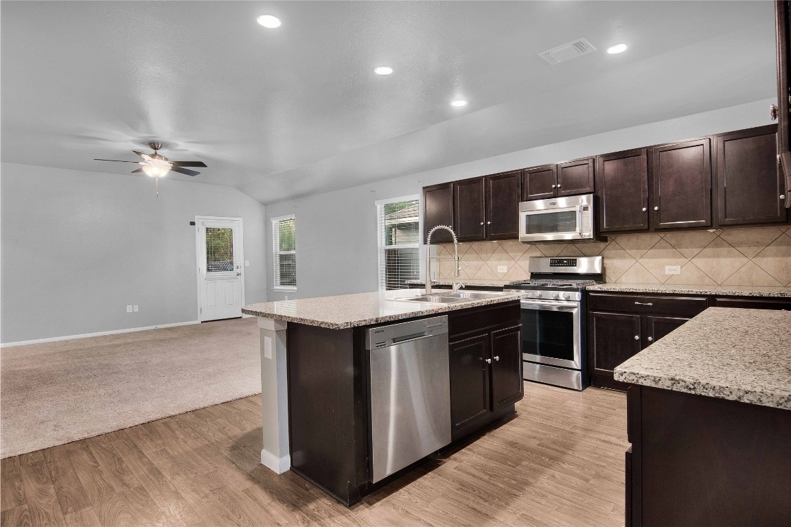 704 Red Tails Drive Austin, TX 78725 - Photo 13 of 37 a kitchen with stainless steel appliances granite countertop a stove a sink and a refrigerator