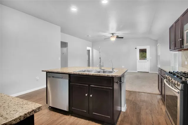 a kitchen with stainless steel appliances granite countertop a stove a sink and a refrigerator