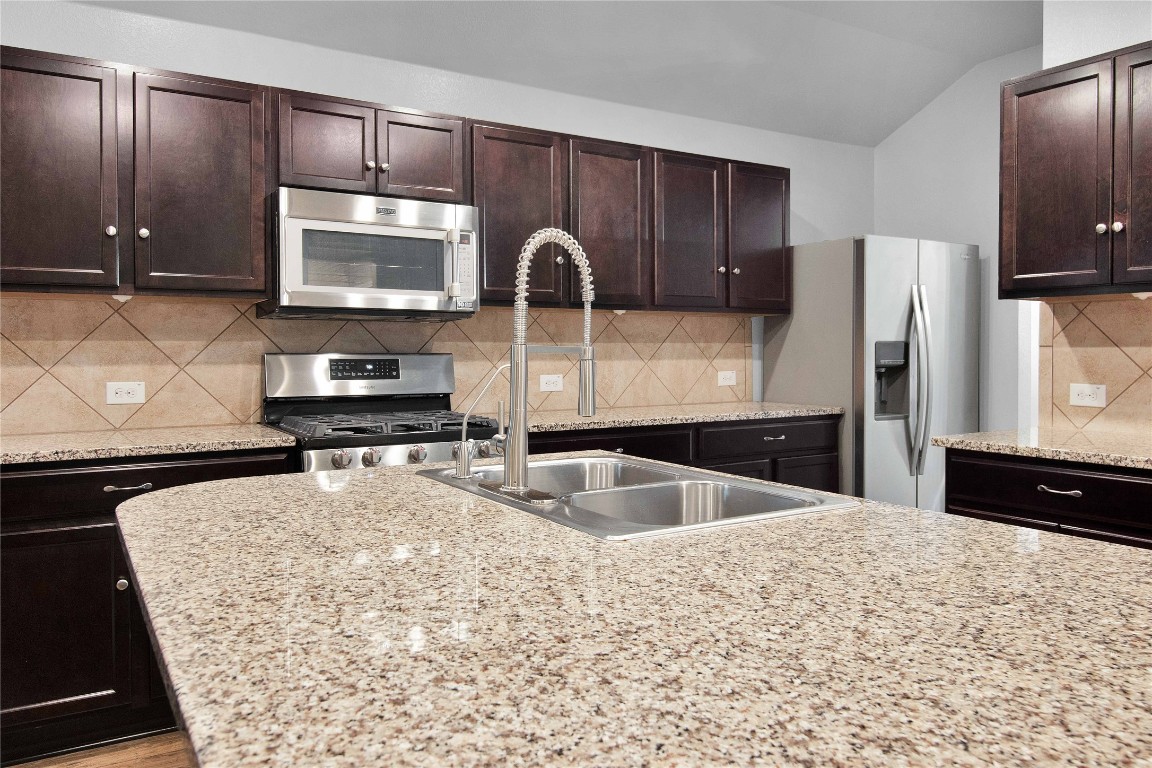 704 Red Tails Drive Austin, TX 78725 - Photo 9 of 37 a kitchen with stainless steel appliances a sink a stove a microwave a counter top space and cabinets