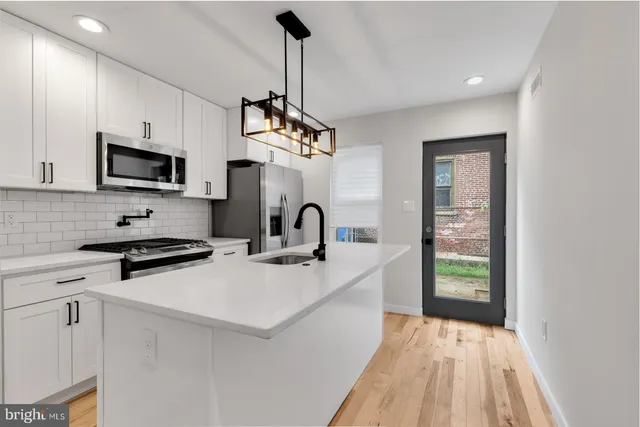 a kitchen with stainless steel appliances granite countertop a stove a sink dishwasher a microwave oven with white cabinets and wooden floor