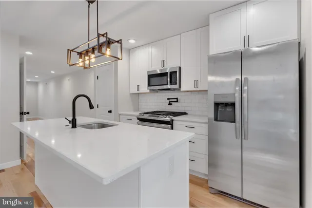 a kitchen with kitchen island stainless steel appliances a refrigerator a sink and a stove top oven