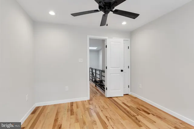 an empty room with wooden floor closet and ceiling fan