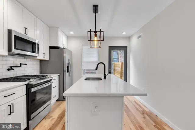 a kitchen with stainless steel appliances granite countertop a sink a stove a refrigerator cabinets and a dining table