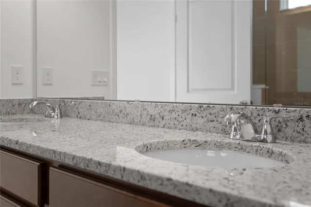 a bathroom with a granite countertop sink and white cabinets