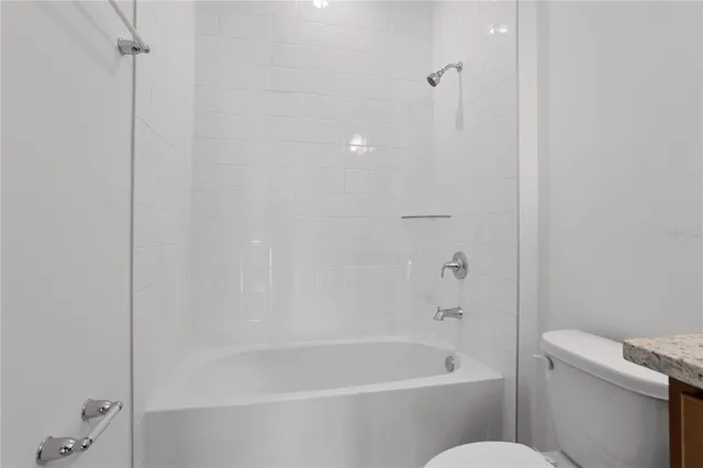 a bathroom with a granite countertop toilet a sink and bathtub