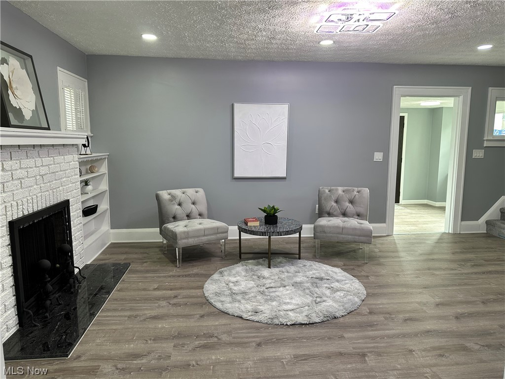 326 Babbitt Road Euclid, OH 44123 - Photo 8 of 26 Living area featuring a textured ceiling, a brick fireplace, and wood-type flooring