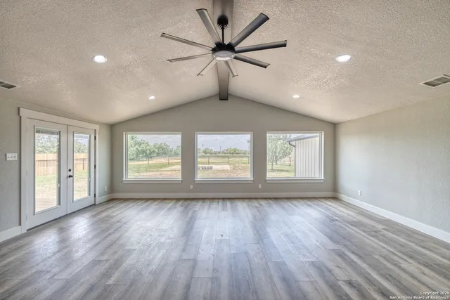 a view of an empty room with a window and wooden floor