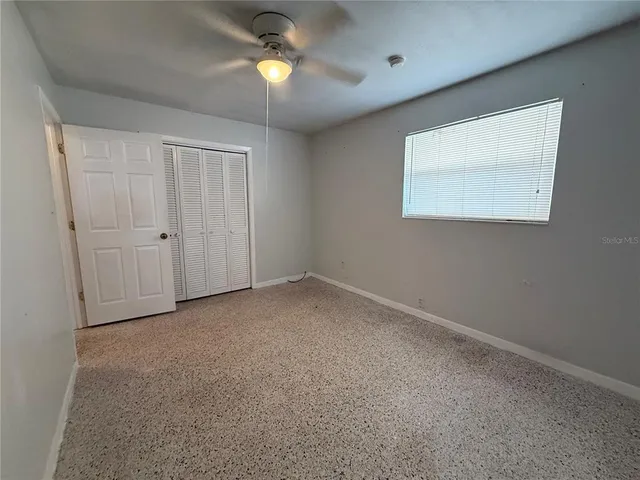 an empty room with a window and a ceiling fan