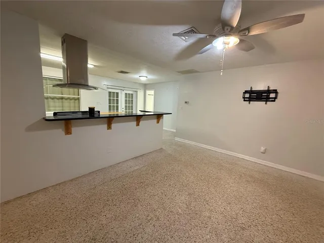 an empty room with kitchen view and a wooden floor