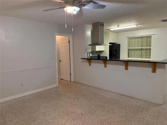 an empty room with chandelier fan and windows