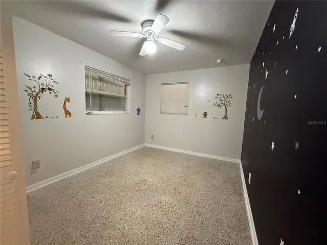 en empty room with windows and ceiling fan