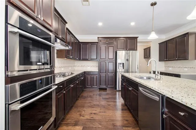 a kitchen with stainless steel appliances granite countertop a stove and a wooden floors