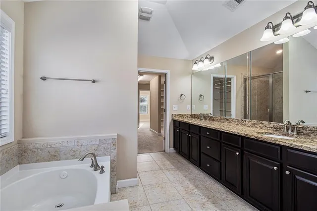 a bathroom with a granite countertop double vanity sink and mirror