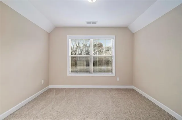 a view of an empty room with closet and bathroom