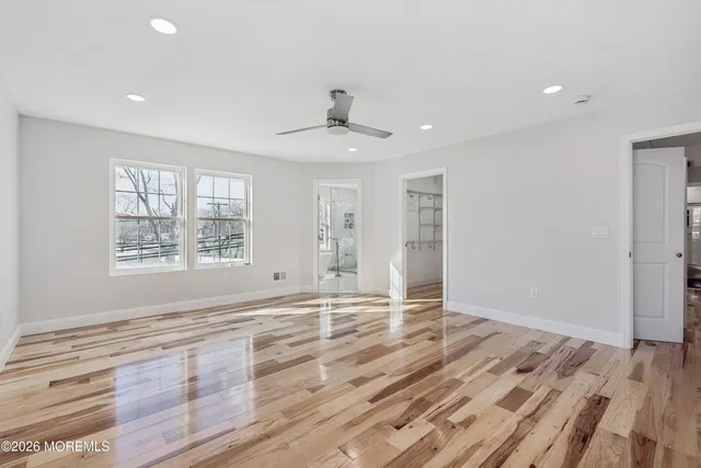 an empty room with wooden floor fan and windows