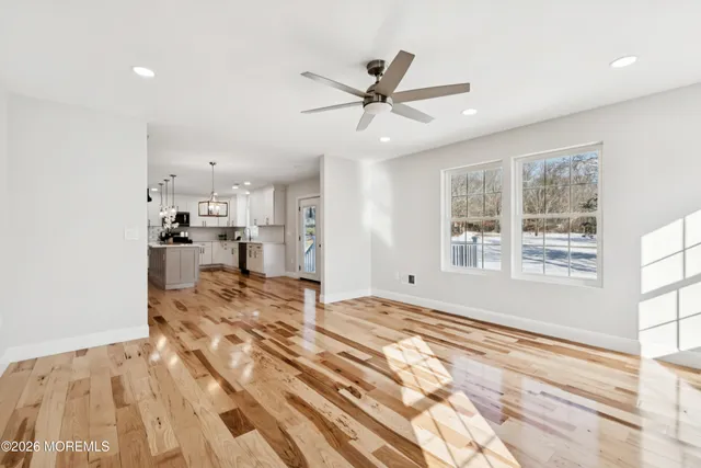 an empty room with wooden floor fan and windows