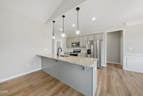 a kitchen with stainless steel appliances a refrigerator a sink and wooden floor
