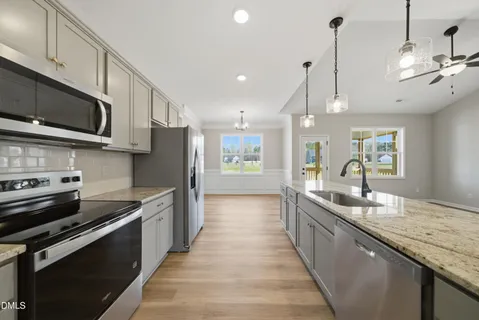 a large kitchen with stainless steel appliances granite countertop a sink a stove top oven a counter space and cabinets