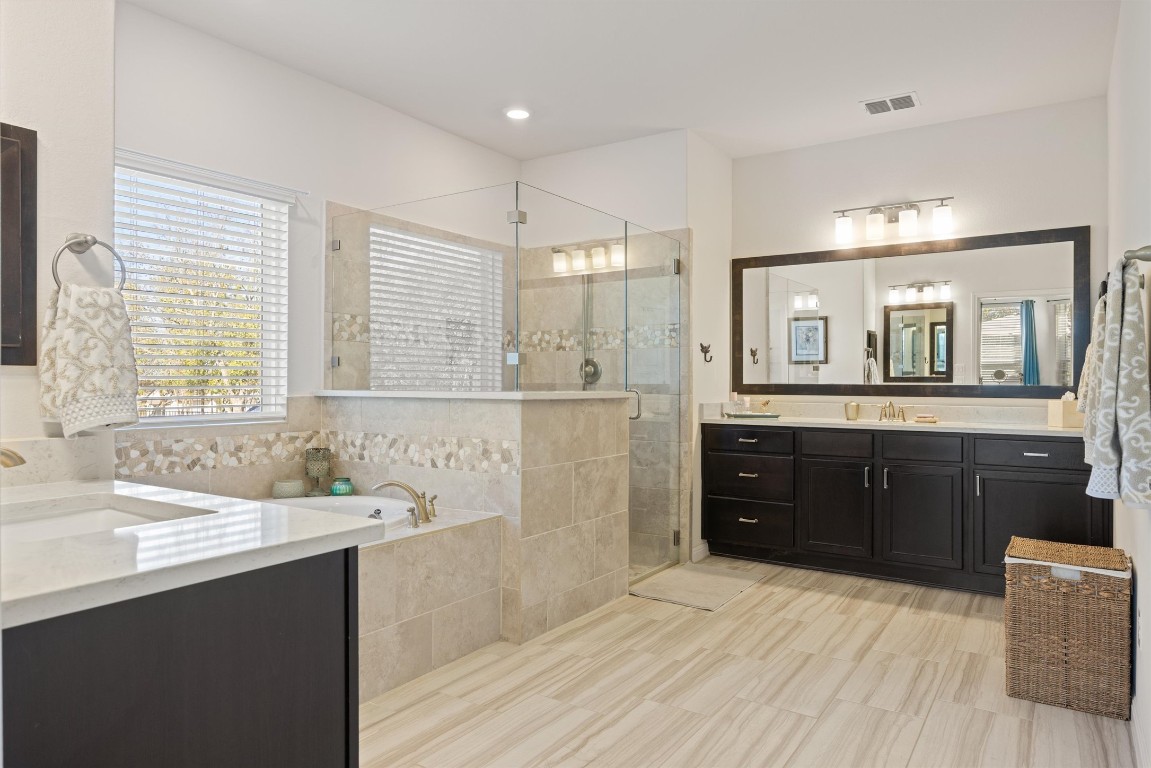 210 Raptor Beak Way Cedar Creek, TX 78612 - Photo 13 of 36 a spacious bathroom with a vanity a sink a mirror a bathtub and window